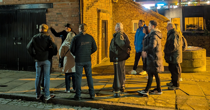 group of people standing while a ghost walk tour guide tells a tale in Durham City.